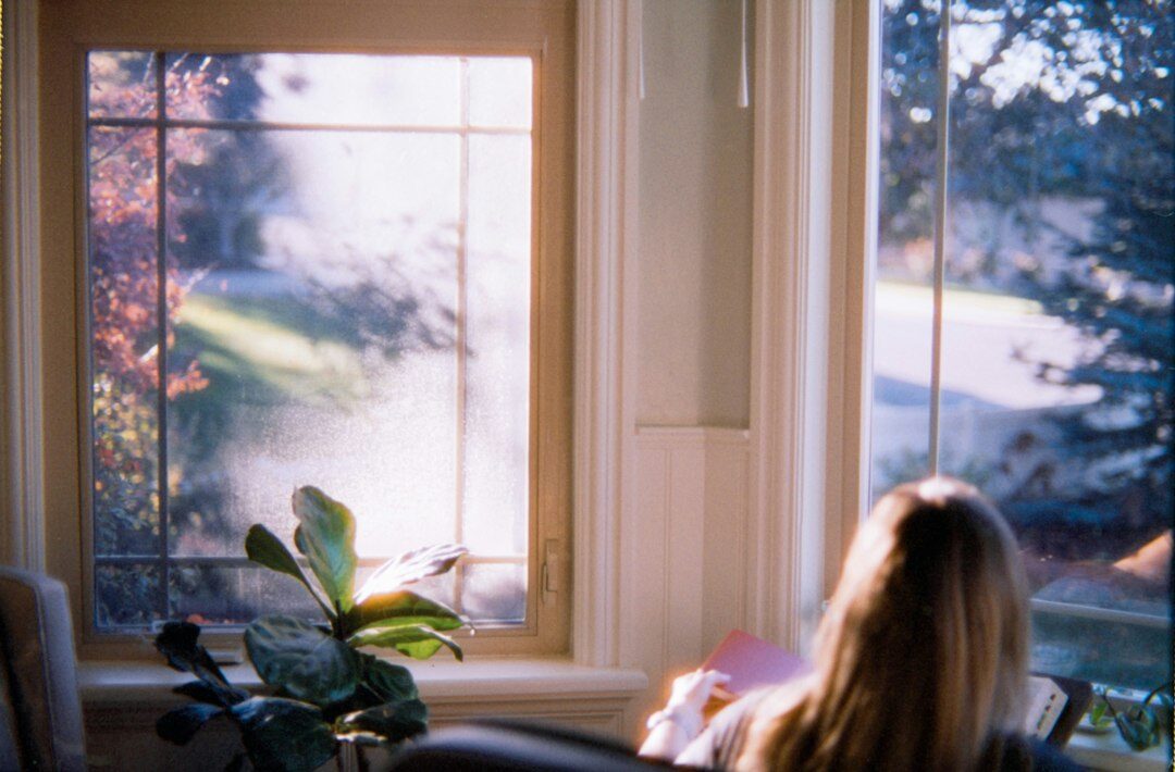 Woman reading a book by a window in warm light